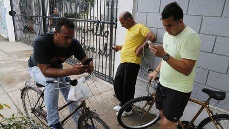 People stand in front of a center run by famed artist Kcho, to use the free Wi-Fi network, in Havana, Cuba, Wednesday, March 11, 2015