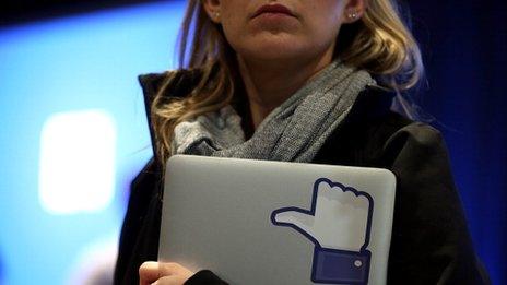 woman holding laptop with Facebook like sticker