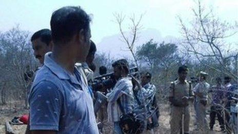 A security guard looks on as members of the media film the bodies of loggers killed by an anti-smuggling task force in a remote forest in the southern state of Andhra Pradesh on April 7, 2015.