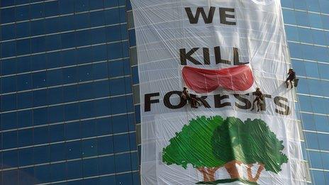 Activists from the environmental group Greenpeace drape the headquarters of India's Essar Group with a giant banner during a protest in Mumbai on 22 January, 2014