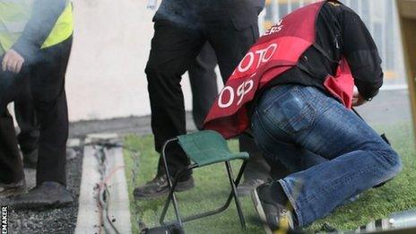 Photographer Daren Kidd falls after being struck during the match at Windsor Park