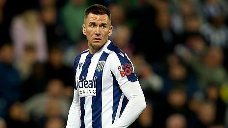 Jed Wallace in match action wearing a navy blue and white striped West Brom playing shirt with white shorts and the number seven in red on the left leg