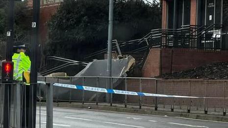 Part of a roof can be seen on the pavement outside a building. 