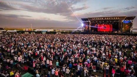 Landscape picture of Lytham Festival with the stage in the background and thousands of people in the crowd.