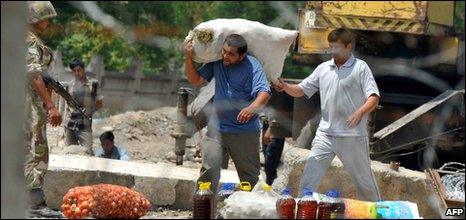 Two men carry provisions at the Kyrgyz-Uzbek border near a village of Nariman outside Osh on June 16, 2010