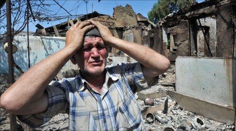 An ethnic Uzbek besides the wreckage of his burned out home in Osh