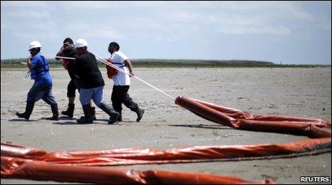 Workers remove oil booms from the beach in Louisiana