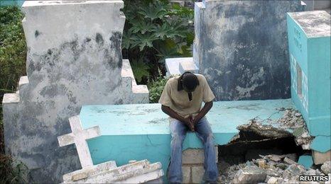 A man prays in a cemetery affected by the 12 January earthquake in Port-au-Prince on 10 July 2010