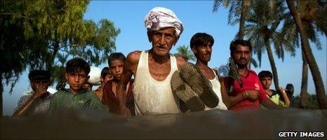 Displaced villagers wade through floodwaters near Muzaffargarh, Punjab province, on 11 August 2010