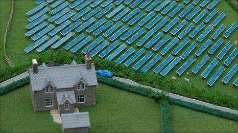 Model of a farm house with solar panels in adjacent field