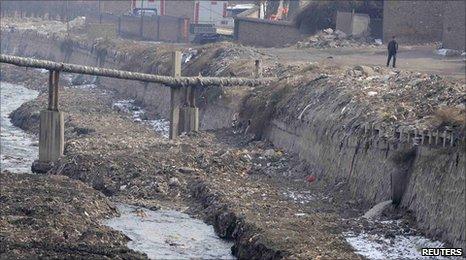 A man walks past a polluted river in Taiyuan, Shanxi, on 2 March 2011