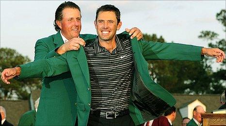 Charl Schwartzel tries on the famous Green Jacket with the help of last year's champion Phil Mickelson