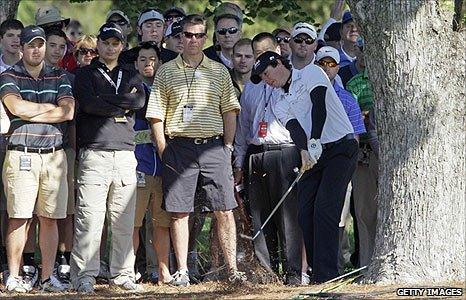 Rory McIlroy plays out from beside a tree on the 16th on the first day of the Wells Fargo Championship