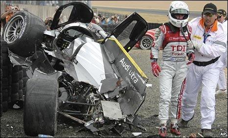 Allan McNish is led from his crashed Audi