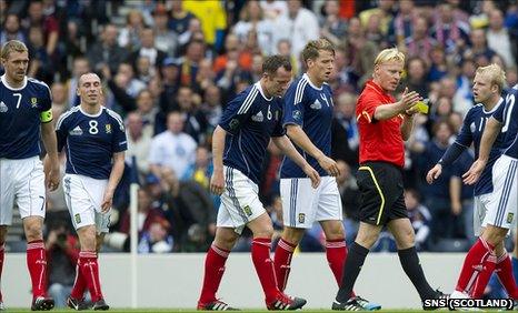 Scotland players surround referee Kevin Blom at Hampden