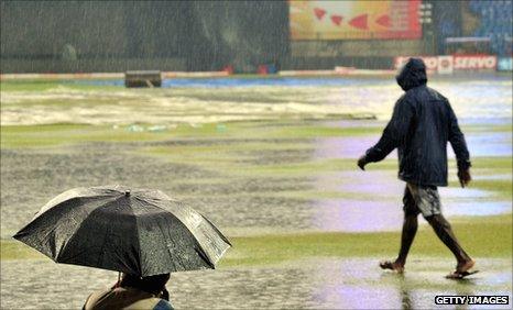 A photographer takes shelter as the rain falls in Bangalore