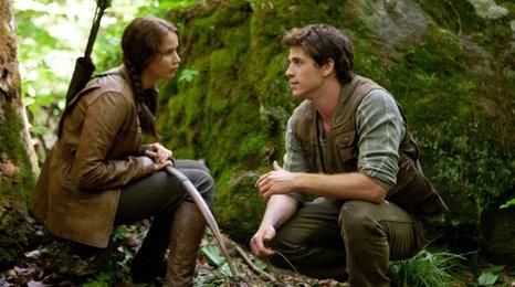 Jennifer Lawrence as Katniss Everdeen and Liam Hemsworth as Gale Hawthorne