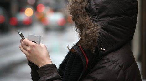 Woman in hooded coat looking at phone