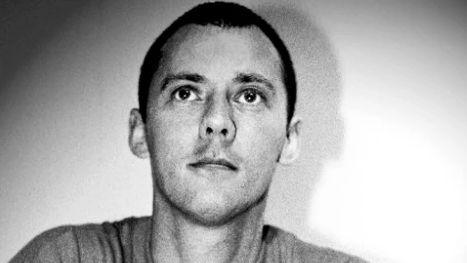 A black and white image of a young man with short dark hair.