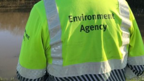 The back of an official wearing a green Environment Agency