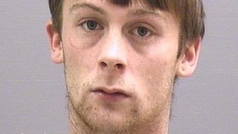 Joe Williams has medium-length brown hair and is unshaven in a police custody photo