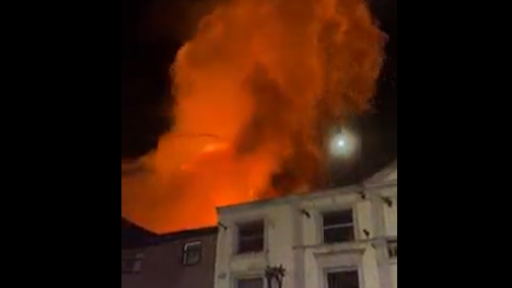 Orange flames leap into the sky from a derelict building behind shops in Church Street, Preston.