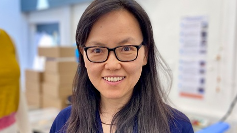 Prof Kai Yang wearing glasses and a blue top in a medical office
