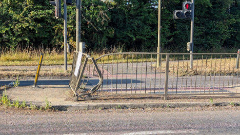 A damaged railing on the A40's crossing. Pictured on a sunny day. There is no one on the road or at the crossing.