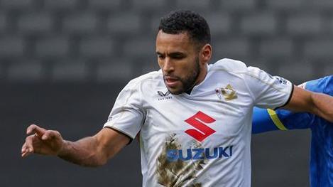 Nathan Thompson uses his left arm to hold off an AFC Wimbledon player