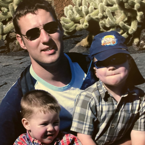 Alistair Wilson in sunglasses holding his two young sons