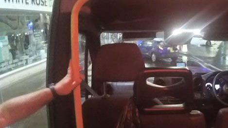 A slightly blurred image of an open taxi with a man's arm holding the handle used to enter the vehicle.
