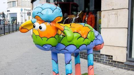 A colourfully decorates statue of a sheep 