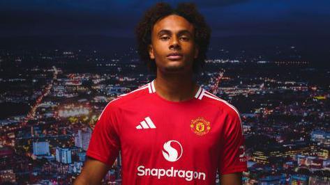 Joshua Zirkzee poses in Manchester United kit