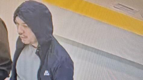 CCTV of escaped prisoner with a black moustache wearing a navy blue puffer jacket with the hood over his head and grey t-shirt.