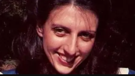 A woman with long dark hair against a dark background