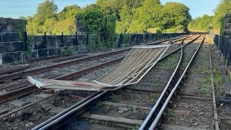 A damaged barrier lying on a railway track.