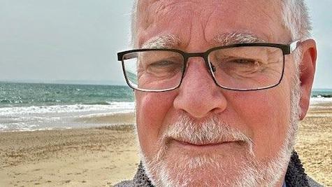 Ian is pictured in a selfie on the beach with a neutral expression