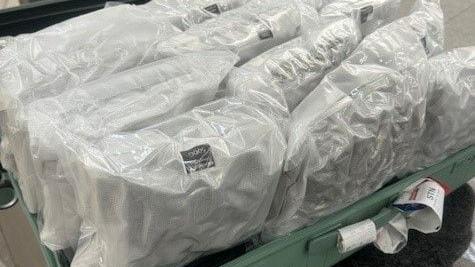 A bundle of vacuum packed white plastic bags full of cannabis, loaded into a green suitcase.