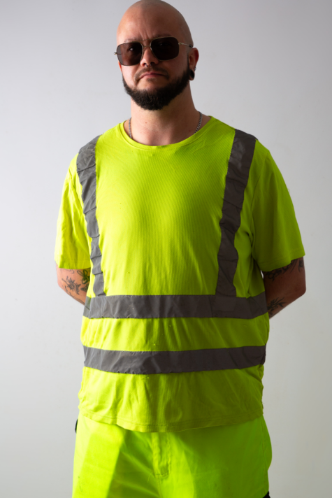 A bald man with a beard is wearing high visibility clothes. He's also wearing sunglasses.