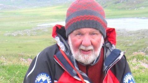 Mike France wearing a red hat and red mountain rescue jacket 