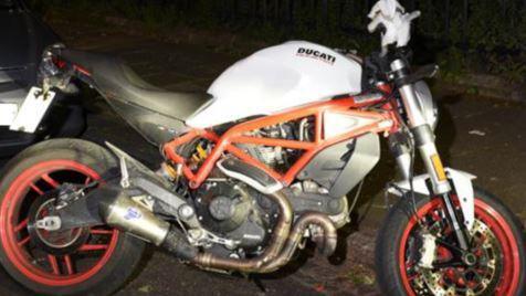 A flash photography image of a  Ducati Monster motorcycle in black, white and red. 