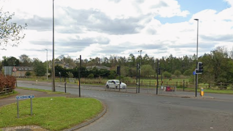 A road junction with a white car sitting at traffic lights