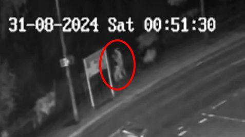 A black and white CCTV image with a red circle highlighting an individual police want to identify.