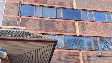 A brown brick building with damp patches.