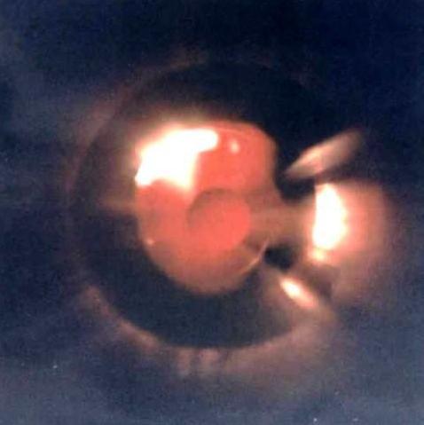A photo of what appears to be a solid craft emanating red light, taken from below.