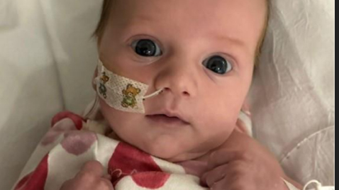Baby Rory Fletcher, wearing red and white pyjamas, in her hospital bed