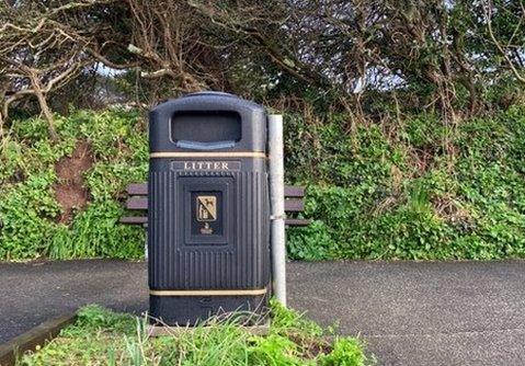 The bin in front of the memorial bench