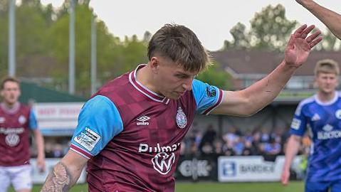 Sonny Finch during a match for South Shields, with his left arm raised for balance, as he tries to cross the ball
