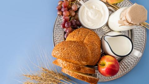 A plate is full of food including milk, apples, bread and wheat