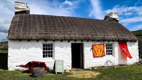 A traditional white cottage with thatched roof.